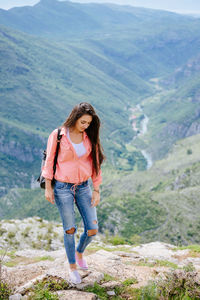 Full length of beautiful woman standing against mountain