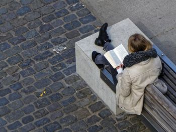 High angle view of woman reading book at sidewalk
