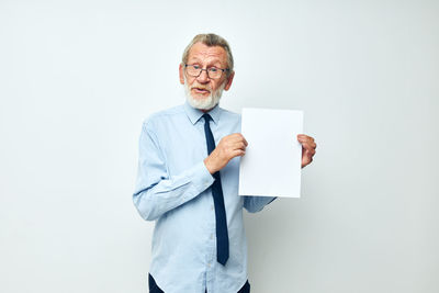 Portrait of young man with arms crossed standing against white background