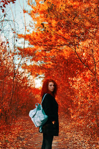 Full length of woman standing by tree during autumn