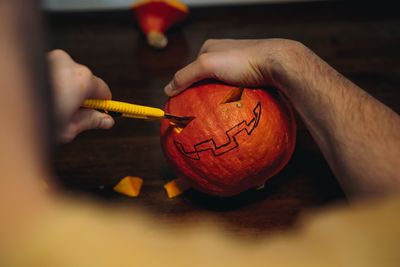 Jack's halloween pumpkin. man's hands carving mouth with paper knife. image with selective focus