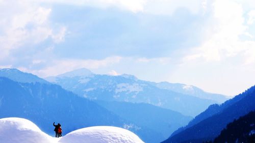 Silhouette couple standing of snowcapped mountains against sky during winter