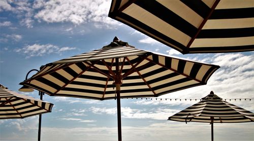 Low angle view of umbrellas on beach against sky