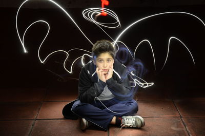 Portrait of boy amidst light painting at night