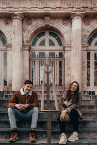 Young couple sitting outside building