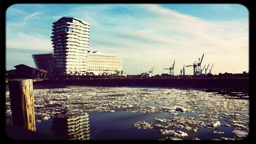 Harbor by river against sky in city