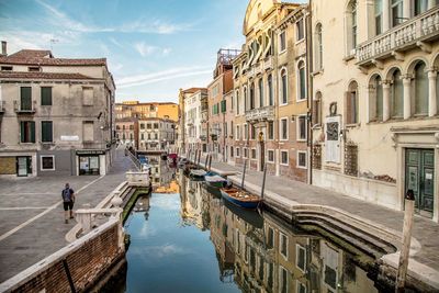 Canal amidst buildings in city against sky