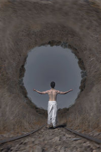 Digital composite image of shirtless man levitating on railroad tracks