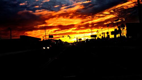 Cars on road against dramatic sky during sunset