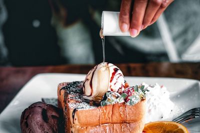 Midsection of person with ice cream cone on table