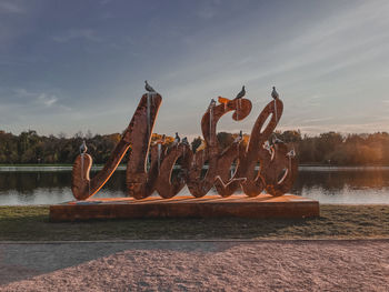 Sculpture by lake against sky