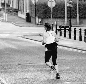 Rear view of woman running on road