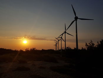 Silhouette of windmill on field against sky during sunset