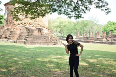 Portrait of young woman standing against trees