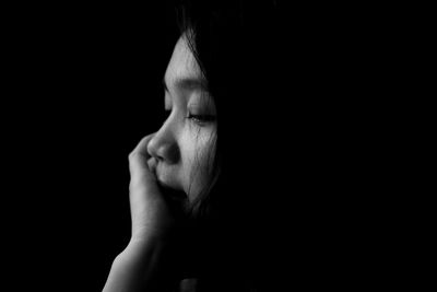Close-up of sad woman against black background