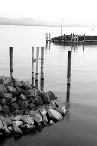 Wooden posts in sea against sky
