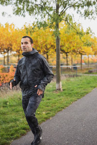 Young man standing on road against trees during autumn