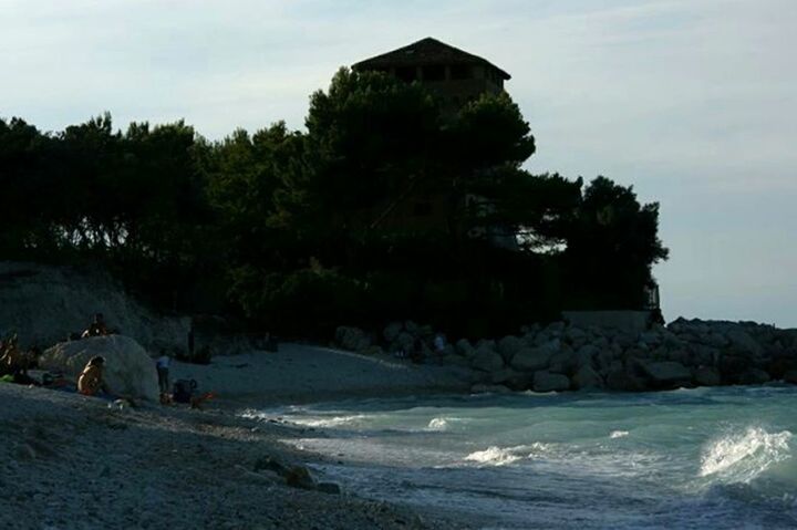 water, architecture, built structure, sea, building exterior, beach, sky, shore, tree, rock - object, rock formation, sand, scenics, nature, travel destinations, waterfront, tourism, vacations, tranquility, coastline