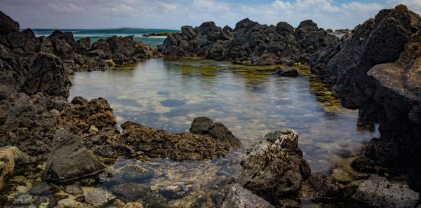 Rocks in sea against sky