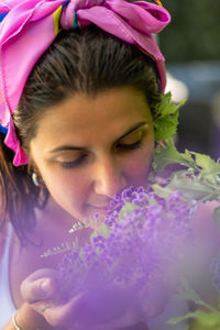 Young woman smelling a violet flower in the garden