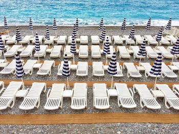 High angle view of empty lounge chairs with closed parasols at beach