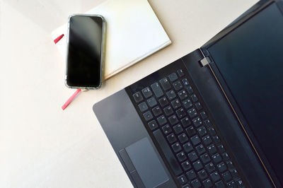 Directly above shot of smart phone and laptop on white desk