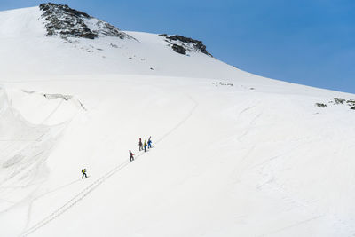 People skiing on snowcapped mountain against sky