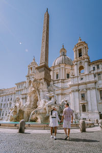 Full length of couple holding hand standing against historical building