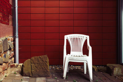 Empty chairs against brick wall
