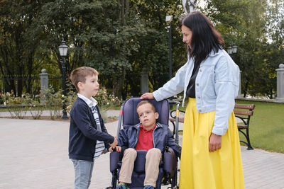 Family with child that has cerebral palsy, wheelchair user walking outdoors. integration