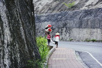 Rear view of people walking on footpath in city