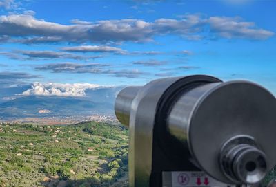 Coin-operated binoculars against sky in city