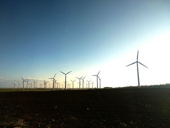 Wind turbines on field against clear sky