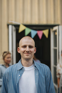 Portrait of smiling young man with shaved head during dinner party at cafe