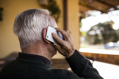 Elderly man talking on the phone on the porch of his house