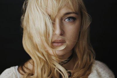 Portrait of young woman against black background