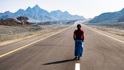 Rear view of man on road against mountain range