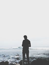 Rear view of man looking at sea against clear sky