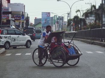 People riding bicycle on road in city