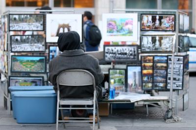 Defocused image of man selling picture frames on street