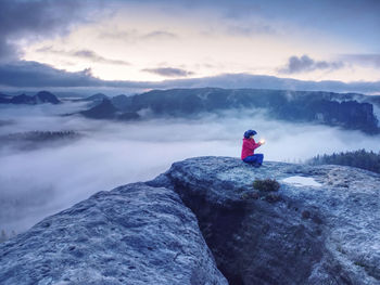 Woman holding lantern. girl alone sit on mountain summit likes ship in misty ocean. mysterious night