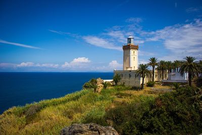 Lighthouse by sea against sky