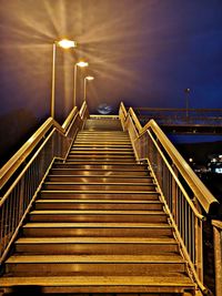 Low angle view of illuminated footbridge against sky at night