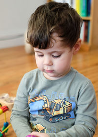 Portrait of a young boy of three playing with a toy in the living room