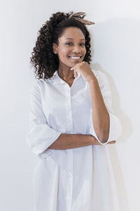 Young woman with hand on chin against white background