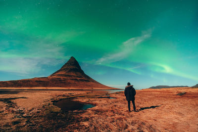 Rear view of man standing on mountain against sky