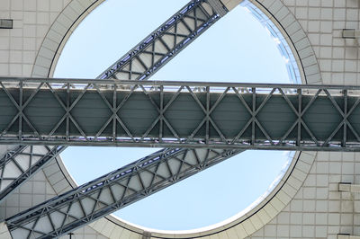 Low angle view of bridge against buildings against clear blue sky