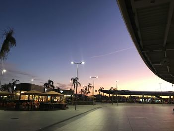 Illuminated street against sky at sunset