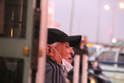 Portrait of man wearing hat standing in city
