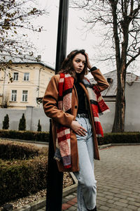 Happy woman standing by tree against building